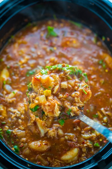 Ladle seafood cioppino into bowls.