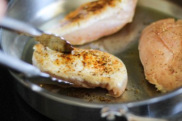 Chicken being flipped in a skillet