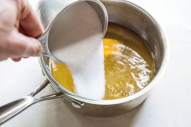 Pouring sugar into saucepan with mint water