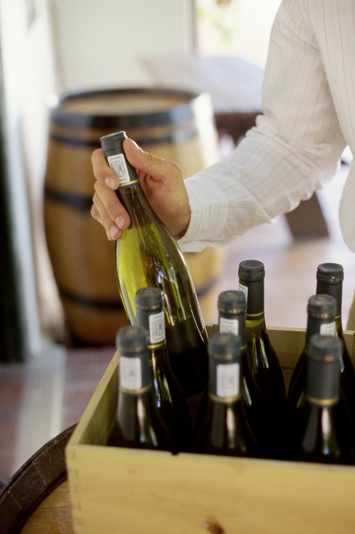 Person\'s hand pulling bottle of wine out of crate