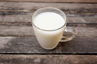 Glass of milk standing on old wooden table