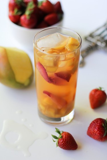 Glass of tropical sangria next to some fresh strawberries.