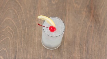 tom collins garnished with lemon wedge and cherry