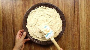 Evening out the top of pie filling for no-bake peanut butter cream cheese pie into prepared pie crust.