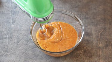 Wet ingredients being beaten in clear glass bowl.