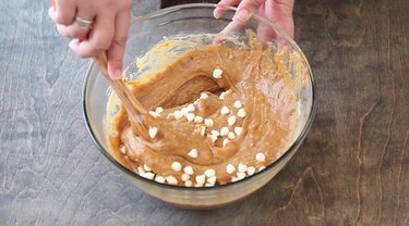 Stirring white chocolate chips into batter.