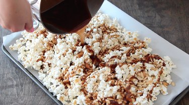 Pouring caramel sauce over popcorn mix.