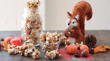 Pumpkin spice caramel corn displayed with mini pumpkins, acorns, and a squirrel figure.