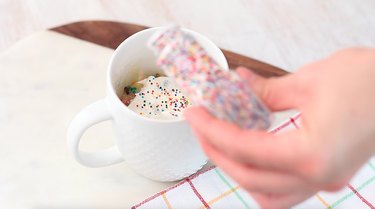 garnishing mug cake with sprinkles