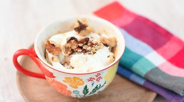 finished carrot mug cake topped with frosting and walnuts