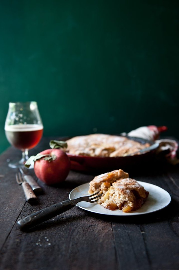 A warm slice of hard apple cider skillet cobbler served with a glass of hard cider.