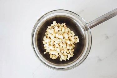 Finely chopped white chocolate set over a saucepan.