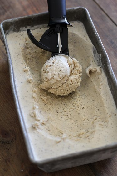 Scoop and container of frozen coffee ice cream.