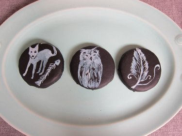 Cookies painted with a cat, owl and feather