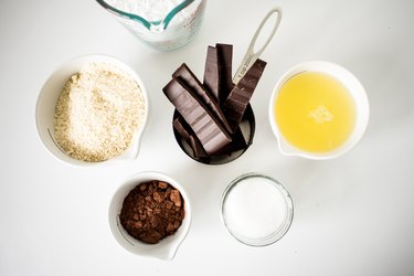 Bowls and measuring cups of chocolate macaron recipe ingredients.