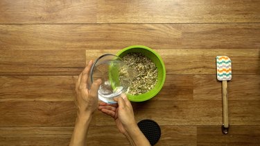 Adding water and coconut oil to seed and nut mixture.