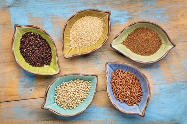 a set of five gluten free grains (sorghum, teff, amaranth,brown rice and quinoa) - top view of leaf shape bowl against grunge, painted wood