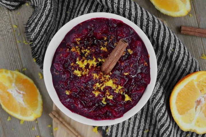 Overhead shot of orange cranberry sauce in a bowl, surrounded by orange wedges