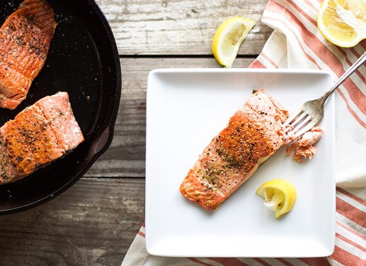 Seared salmon served with lemon wedges