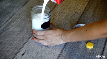 Filling mason jar with milk for freezing.