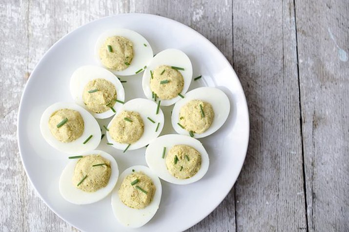 A platter of curried deviled eggs sprinkled with chives.