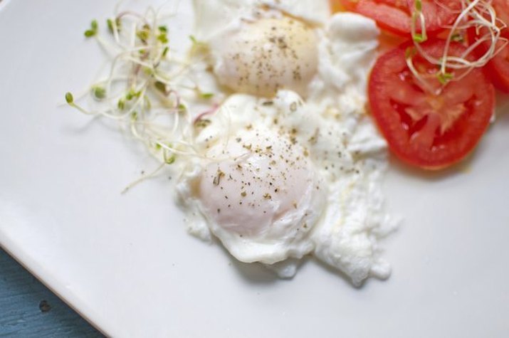 Two neatly poached eggs served with tomatoes.